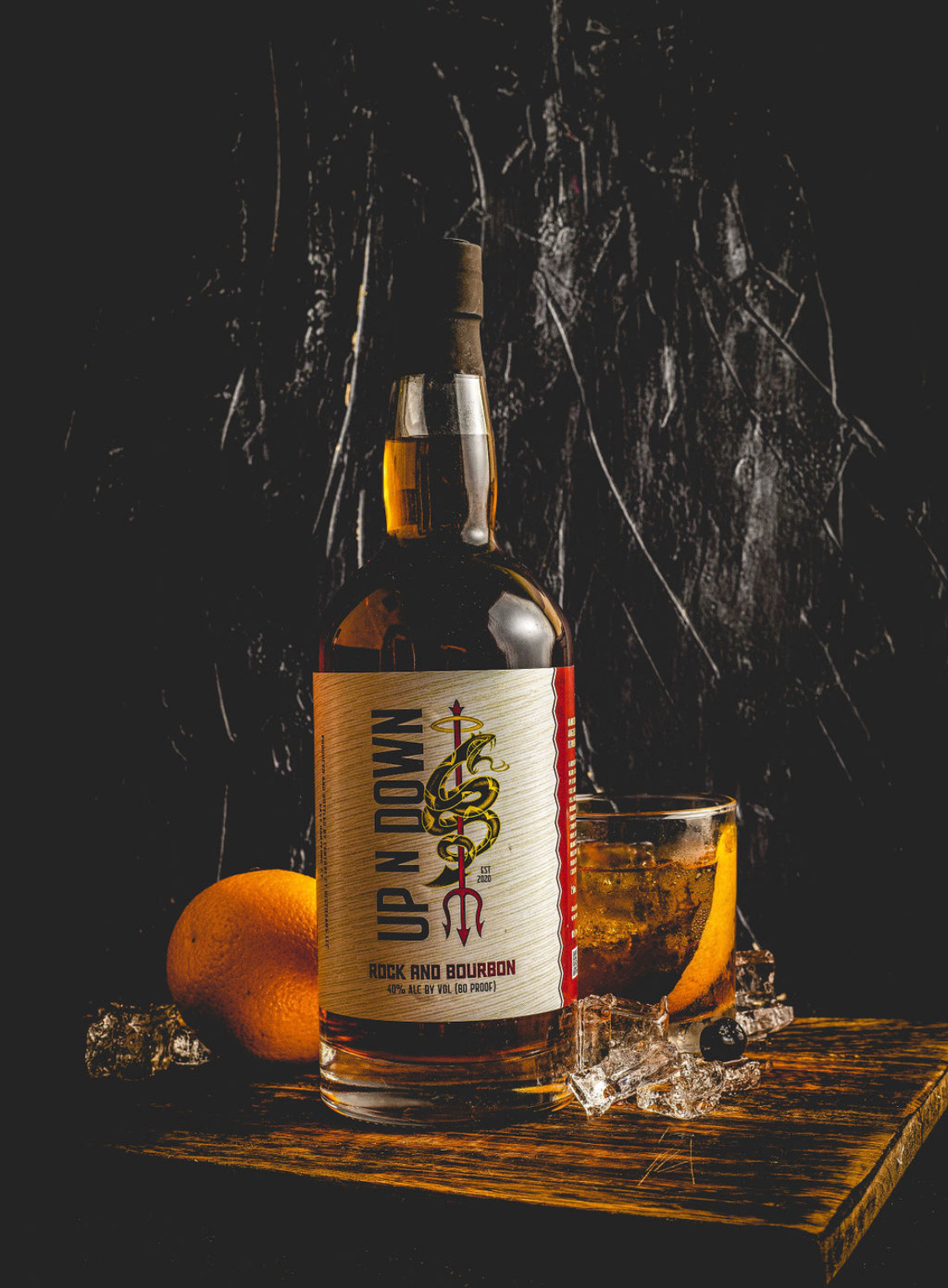 Up N Down Rock & Bourbon bottle beside an Old Fashioned on the rocks with orange and cherry